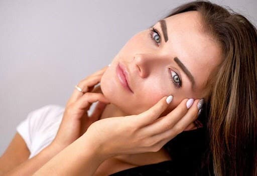 Beautiful woman with clear, glowing skin, showcasing facial skincare results.