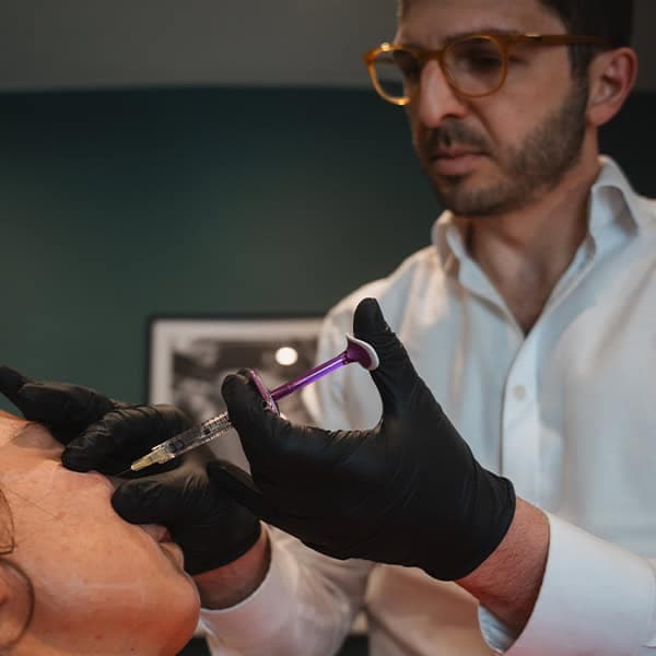Medical professional administering skin treatment with syringe.