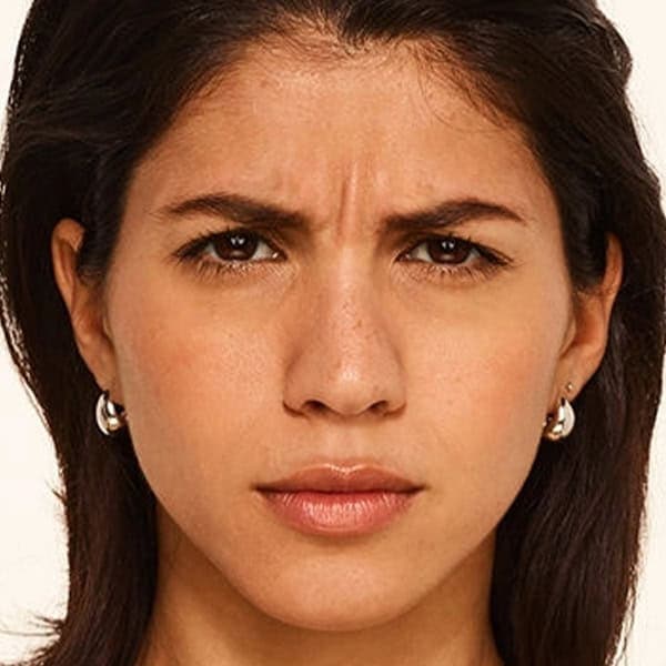 Facial expression of a woman with clear, smooth skin and a serious look.