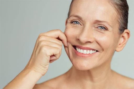Woman with clear, glowing skin smiling, promoting skincare at Cannelle Skin Clinic.