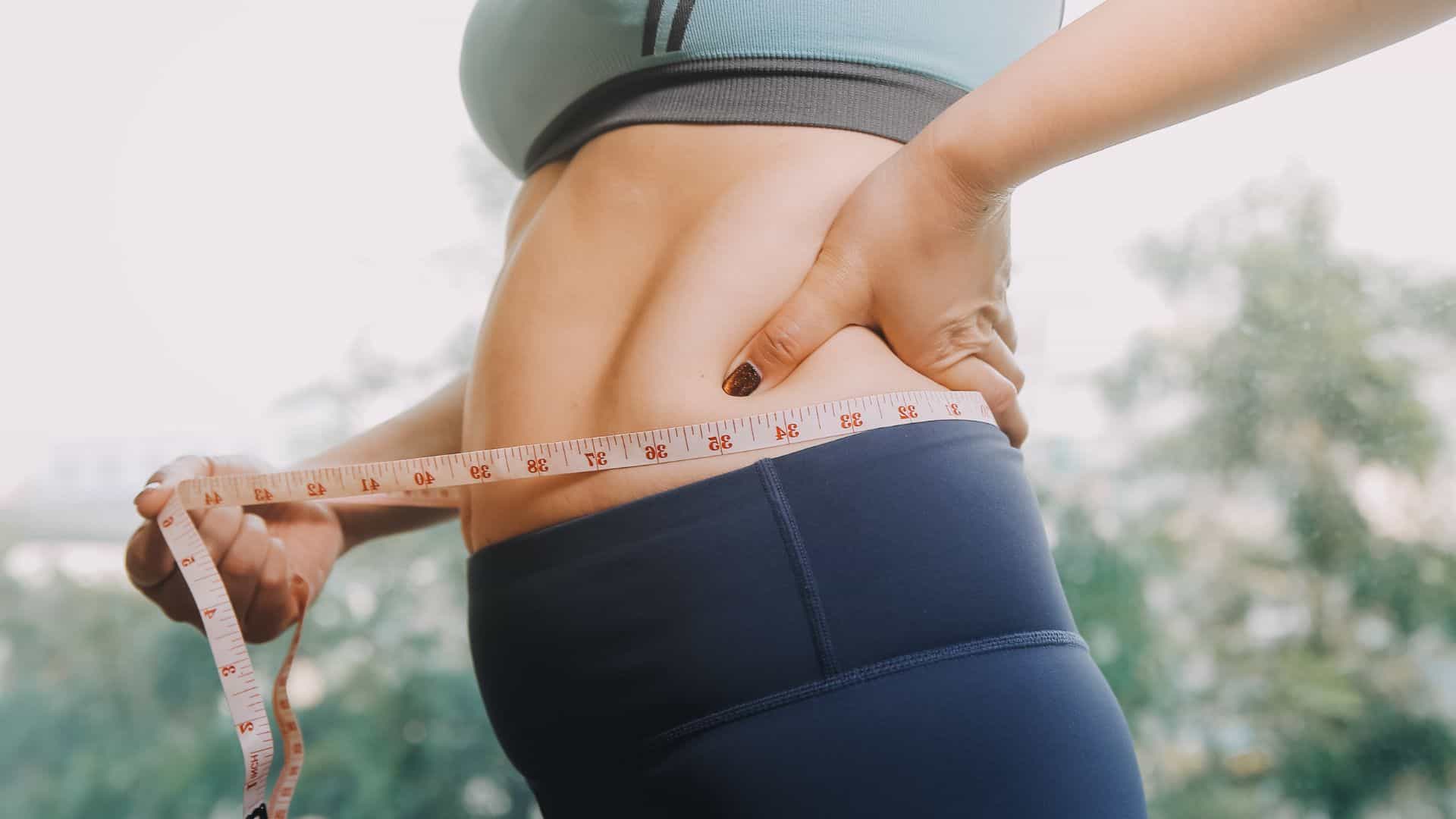Female measuring waist for body sculpting or fat reduction.