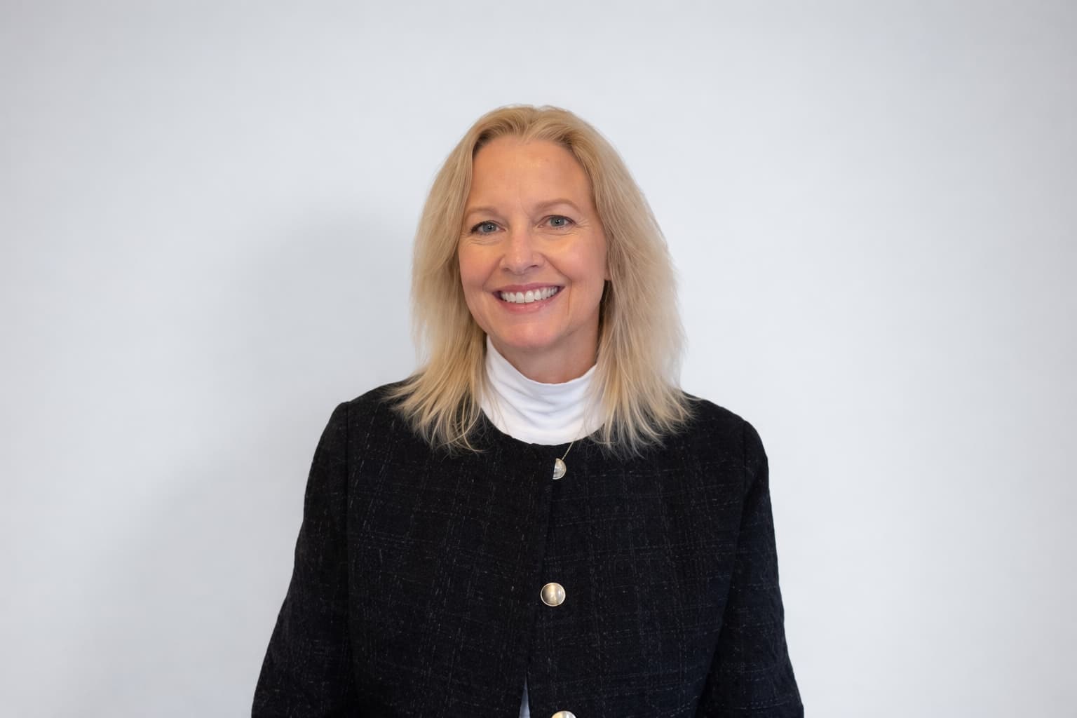 Professional woman at Cannelle Skin Clinic smiling, skincare expert in a black blazer.