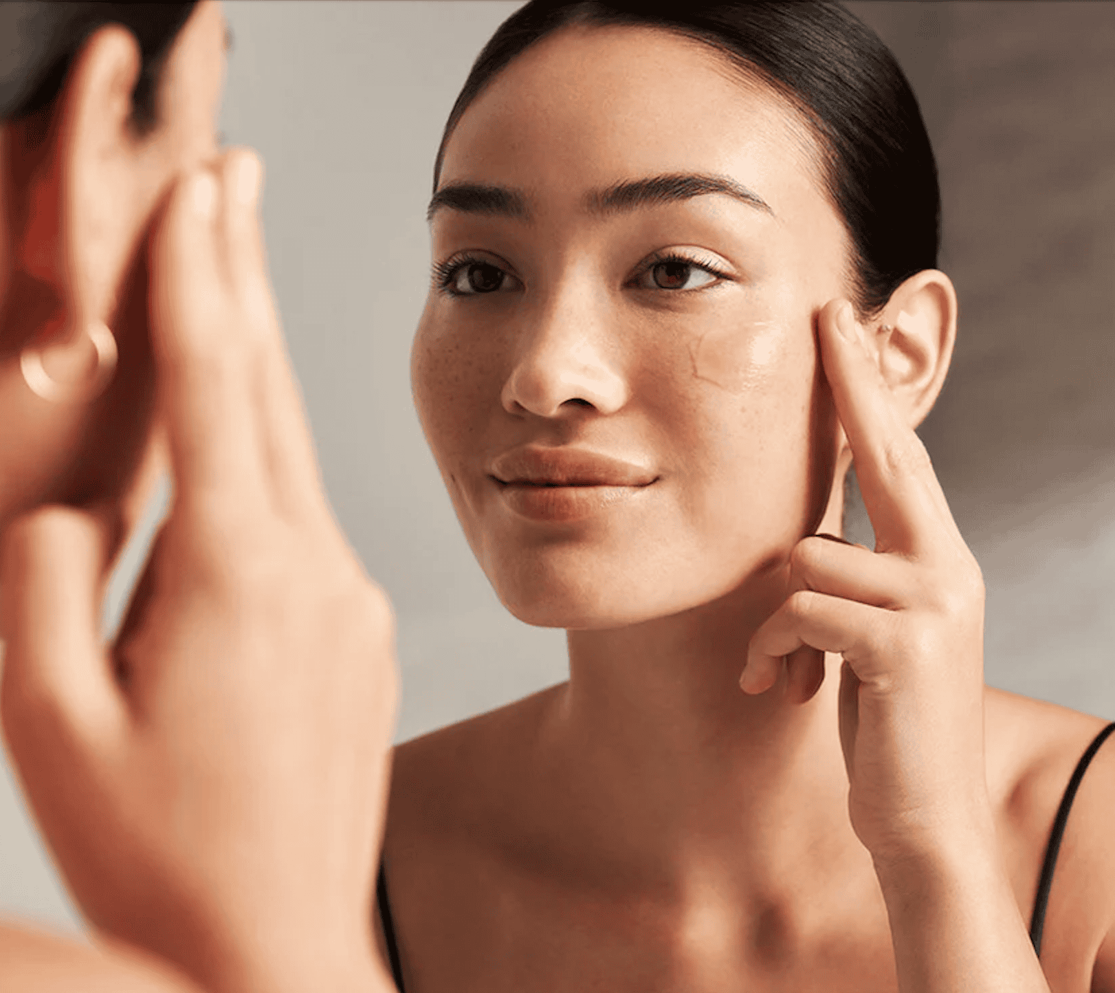 Woman examining her clear, healthy skin during a skincare consultation at Cannelle Skin Clinic.
