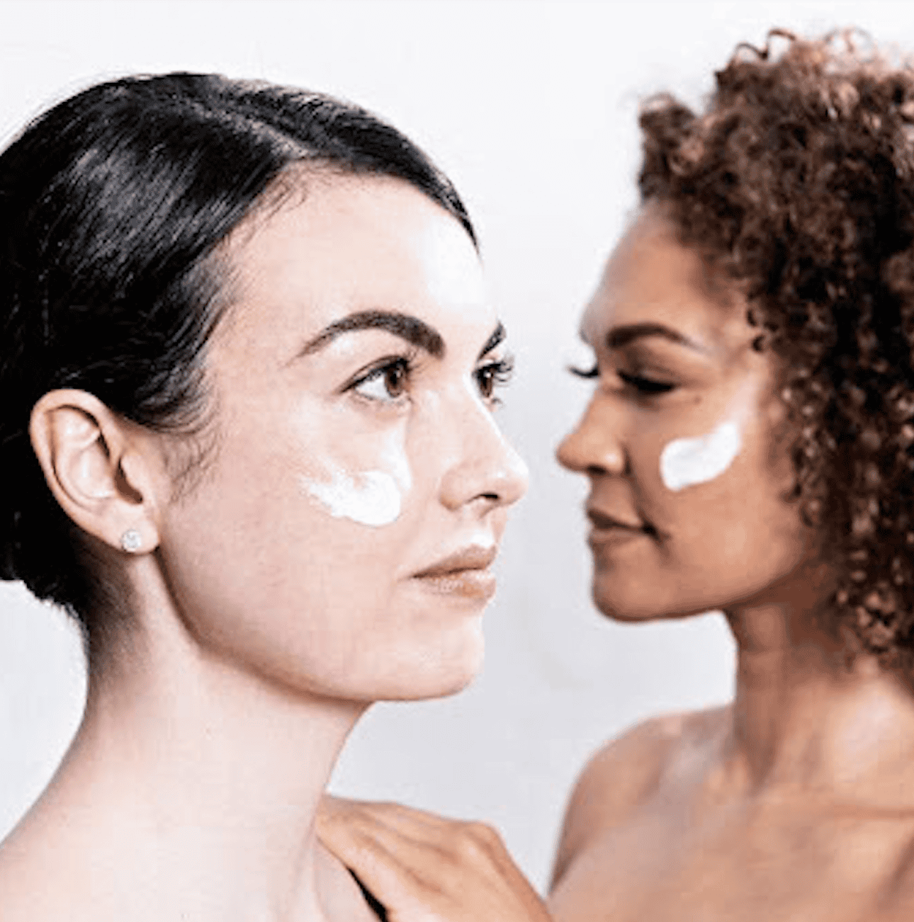 Two women receiving skincare consultation at Cannelle Skin Clinic, applying cream to their faces.