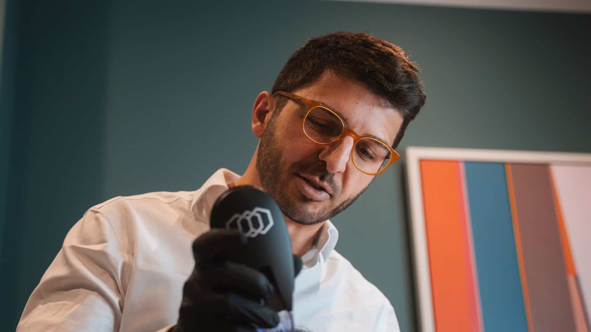 A man in a white coat and glasses holding a microphone during a skin consultation at Cannelle Skin C.
