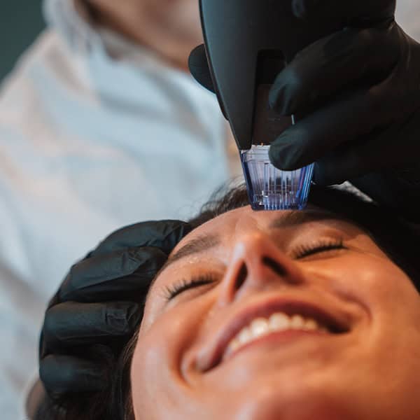 Woman receiving skin treatment with a laser device at Cannelle Skin Clinic.