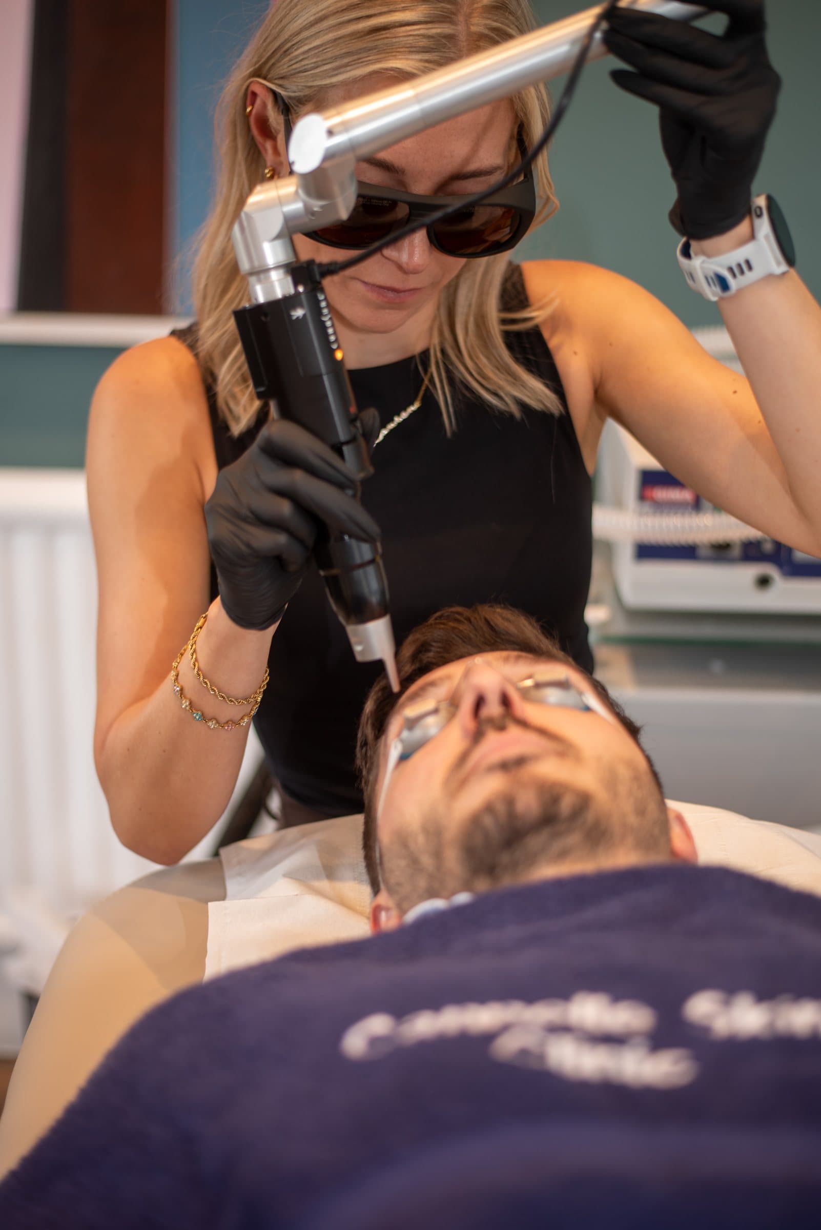 A Cannelle therapist in protective eyewear guides the PicoSure handpiece over a patient's face