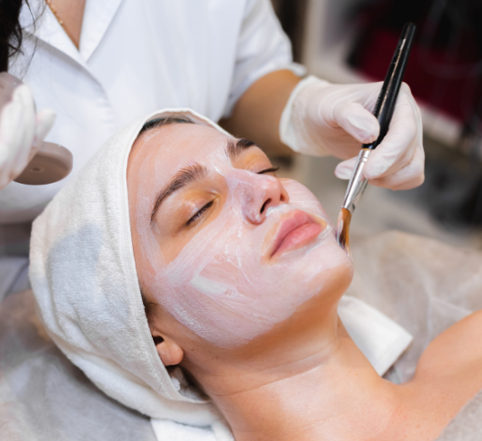 woman undergoing a facial treatment in a beauty salon, with a serene expression and beauty products in the background.