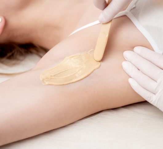 Waxing session with warm wax on woman's underarm